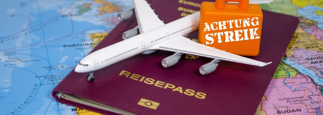 Weltkarte mit Reisepass und kleinem Flugzeug und Koffer mit Streik-Hinweis