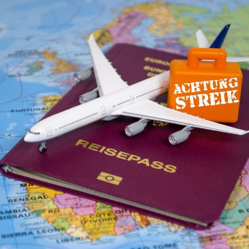 Weltkarte mit Reisepass und kleinem Flugzeug und Koffer mit Streik-Hinweis
