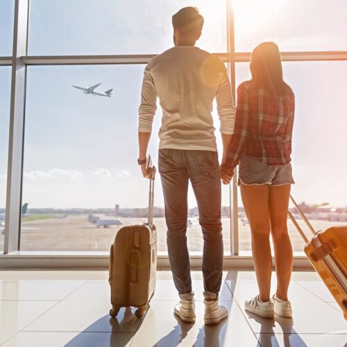 Paar mit Gepäck beobachten steigendes Flugzeug am Flughafen