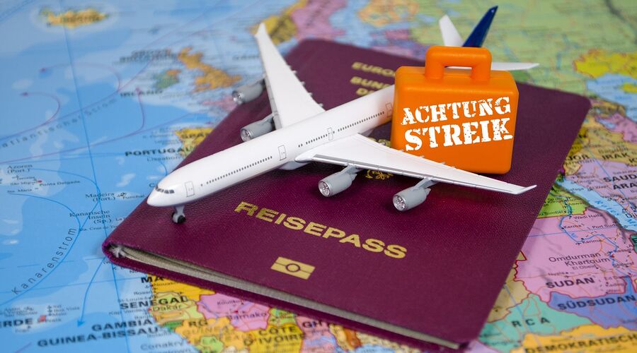 Weltkarte mit Reisepass und kleinem Flugzeug und Koffer mit Streik-Hinweis