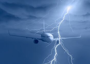 Ein Passagierflugzeug fliegt durch dunkle Gewitterwolken, während Blitze am Himmel zu sehen sind – Symbolbild für einen Blitzeinschlag und wetterbedingte außergewöhnliche Umstände.