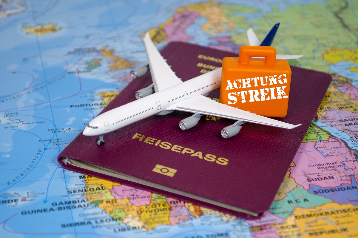 Weltkarte mit Reisepass und kleinem Flugzeug und Koffer mit Streik-Hinweis